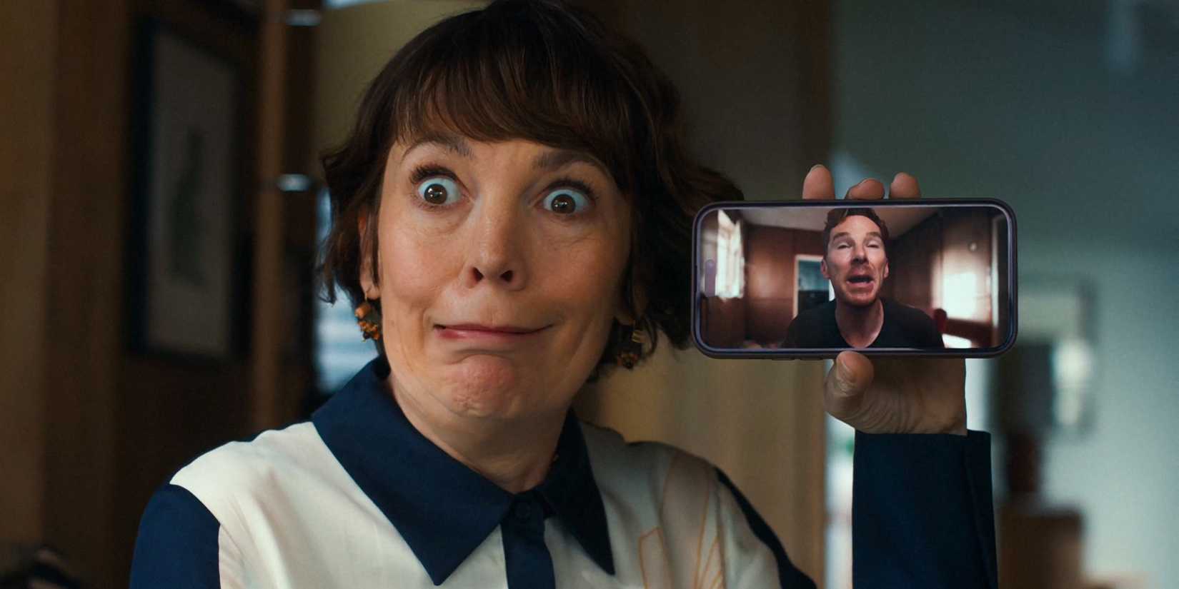 Olivia Colman fazendo uma careta segurando seu telefone com Benedict Cumberbatch nele em The Roses