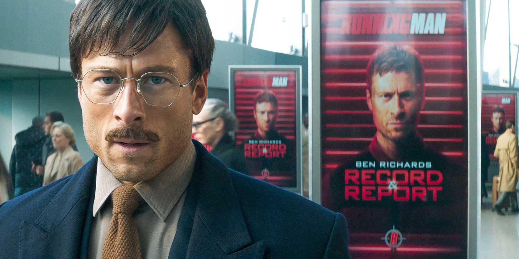 Ben Richards (Glen Powell) disfarçado, com um pôster de seu rosto atrás dele em The Running Man (2025)