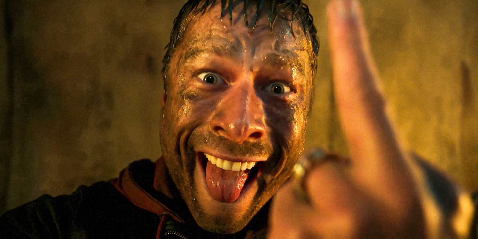 Ben Richards (Glen Powell) with a crazy look, showing the middle finger in The Running Man (2025)