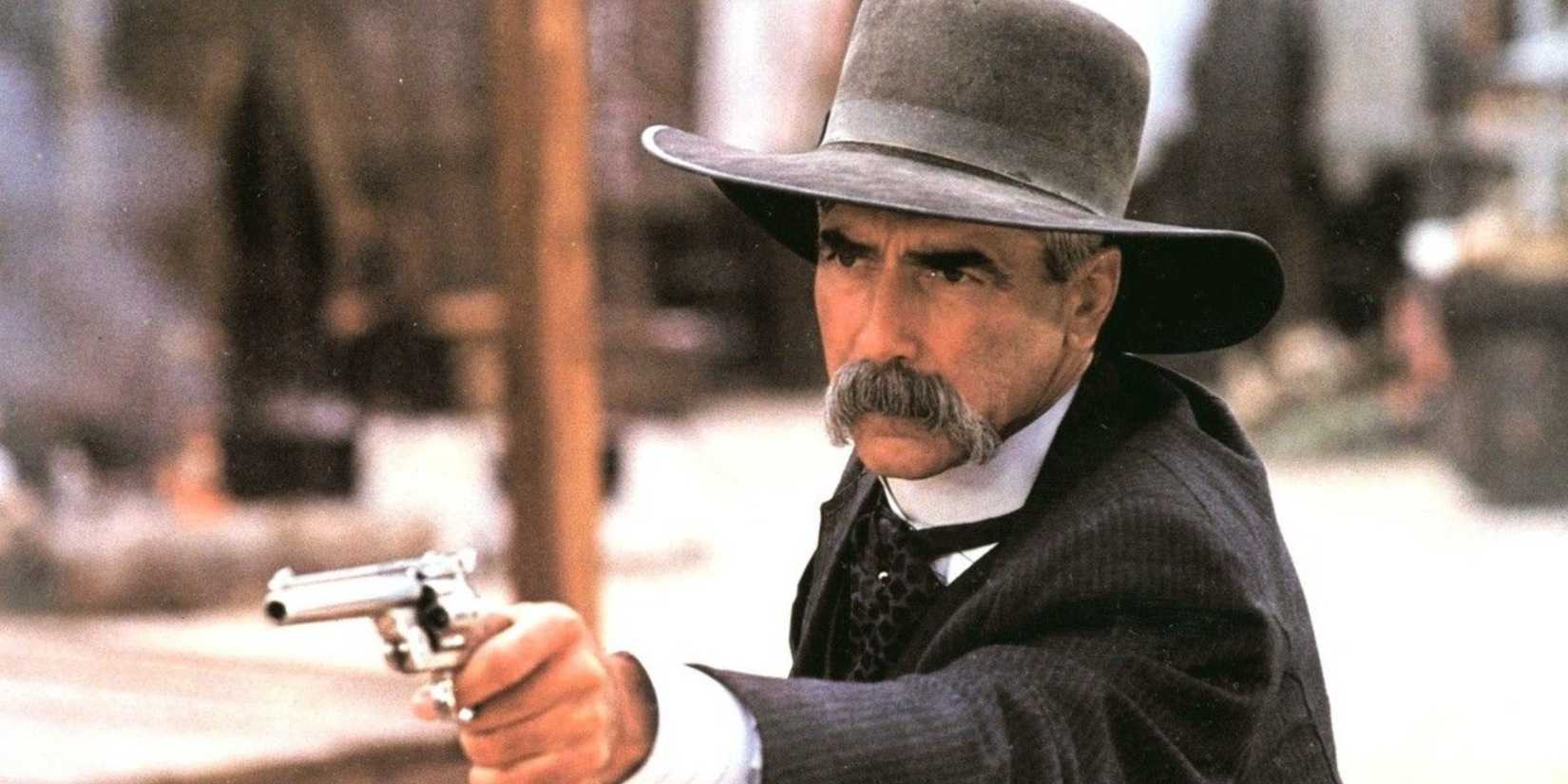 Sam Elliott points a pistol at someone offscreen in Tombstone