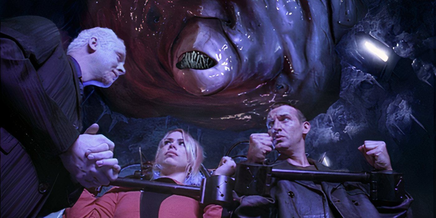 The Ninth Doctor and Rose, wearing handcuffs, talking to the Editor while standing under the Jagrafess on Satellite 5 in the Doctor Who season 1 episode 