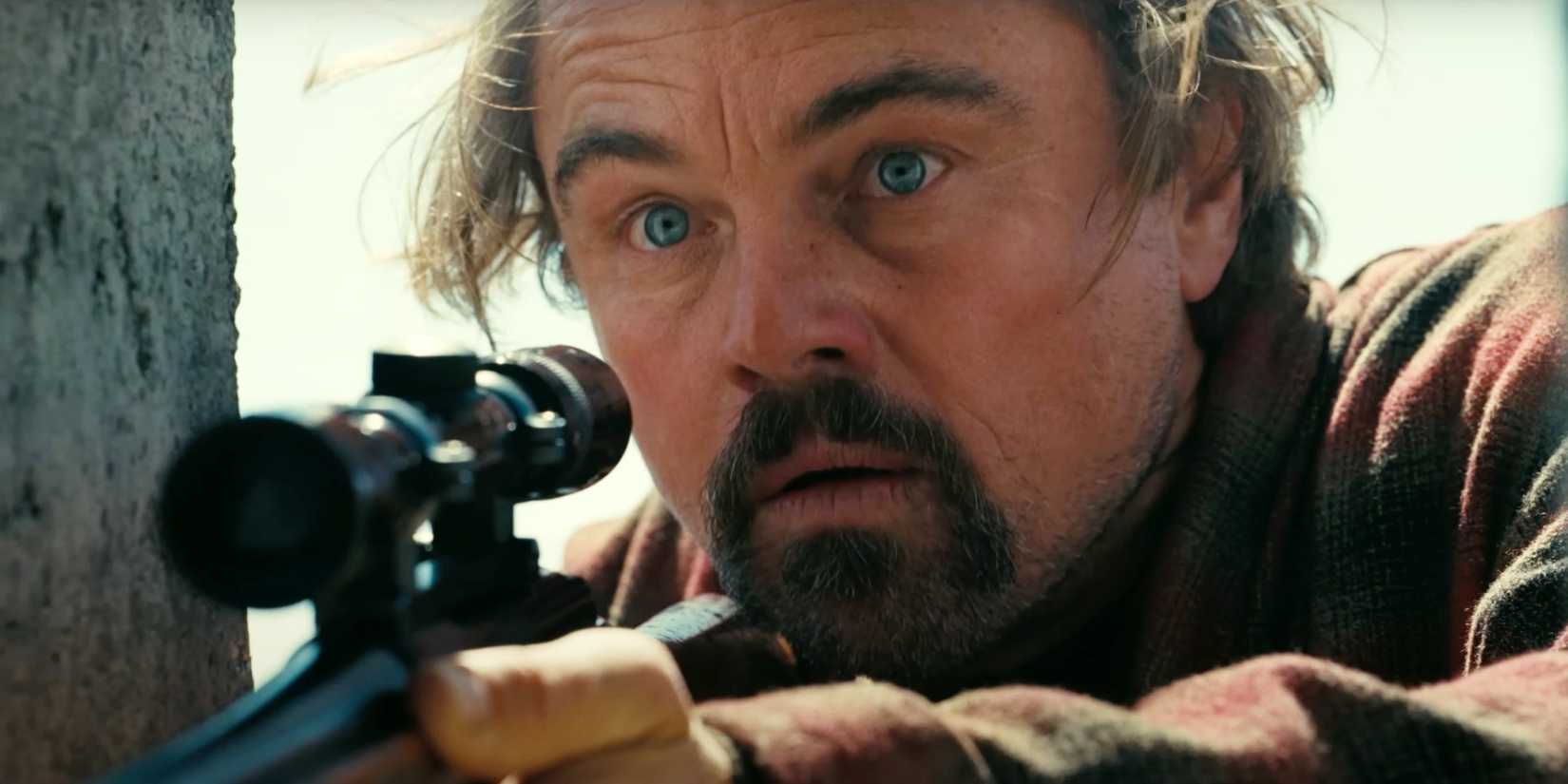 Leonardo DiCaprio looking shocked while holding a rifle in One Battle After Another