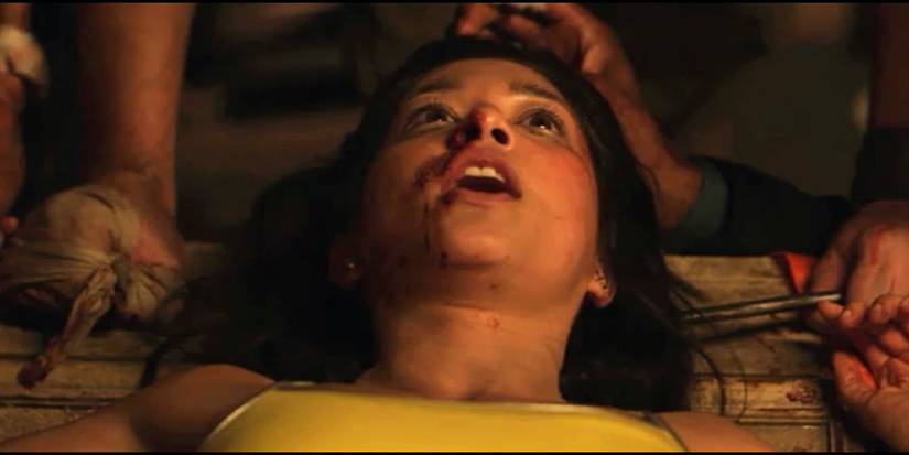 A woman looks up in terror with blood on her mouth in Vile