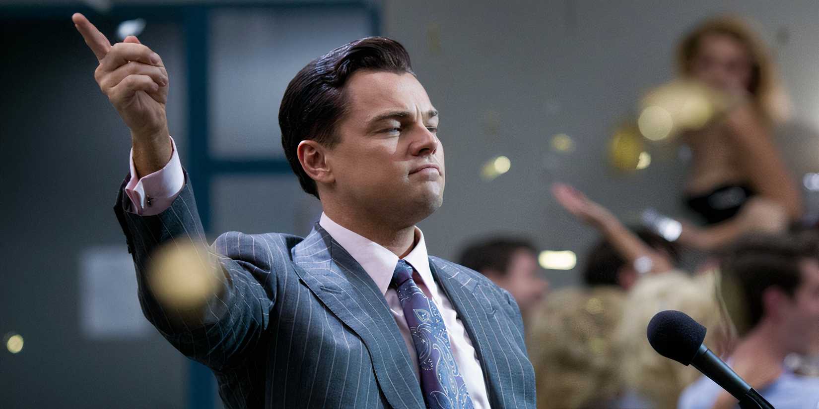 Jordan points into the sky as confetti falls around him at a podium in The Wolf of Wall Street