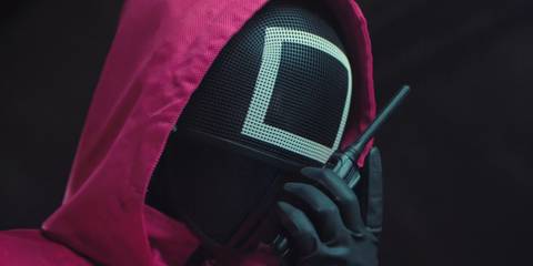 A Squid Game guard talking on a walkie talkie in season 3