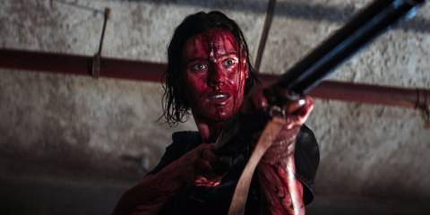 A woman covered in blood holds a gun in Evil Dead Rise