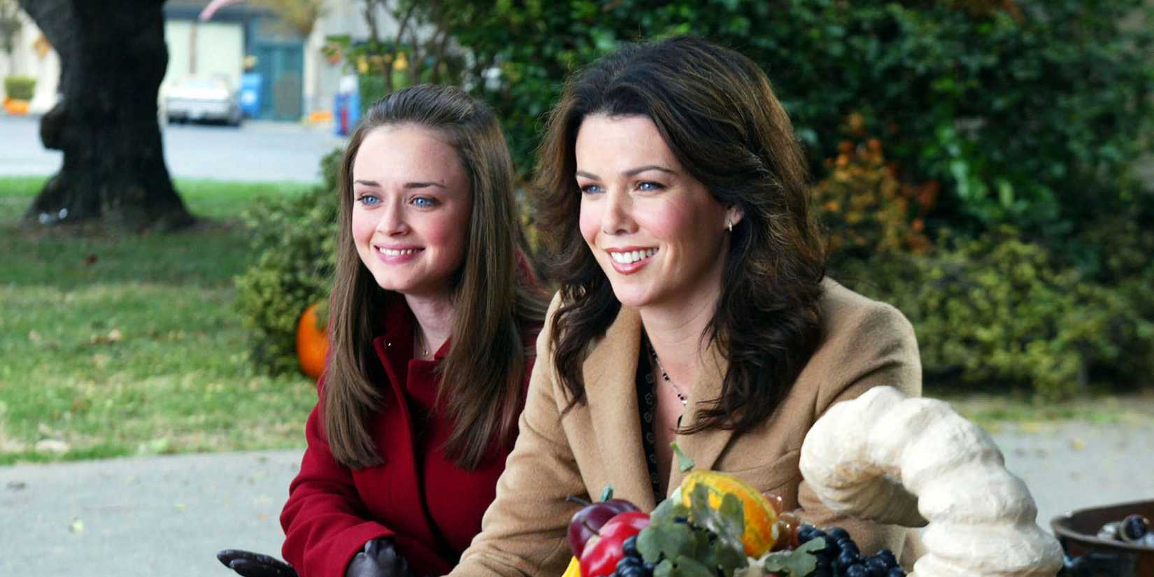 Rory and Lorelai smiling at Sookie's Thanksgiving dinner in Gilmore Girls