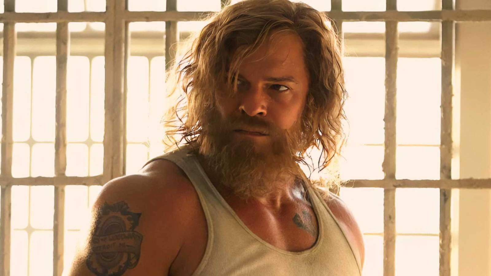 Alan Ritchson standing in front of bars with a tense expression on his face in Motor City