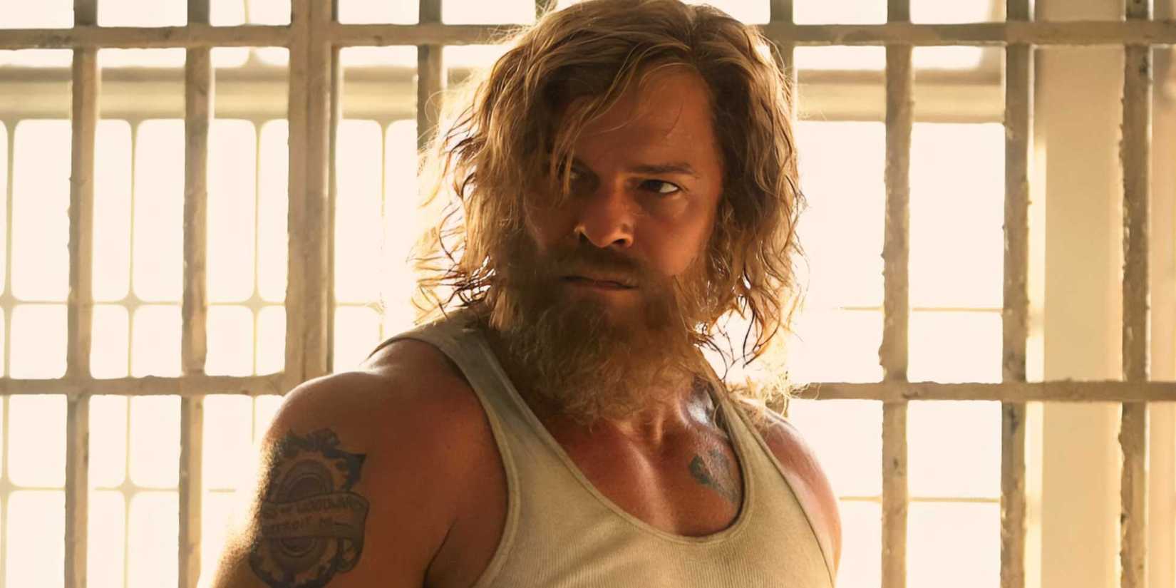 Alan Ritchson standing in front of bars with a tense expression on his face in Motor City