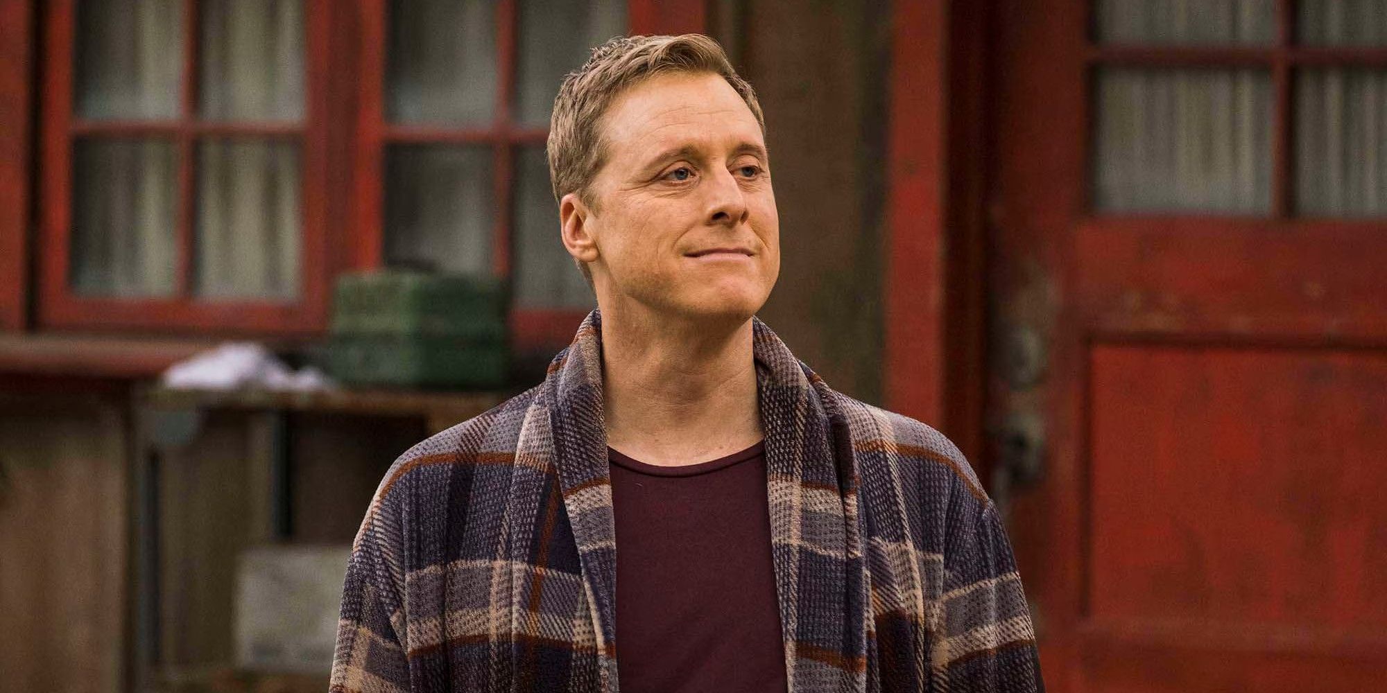 Alan Tudyk stands next to a red door in Resident Alien