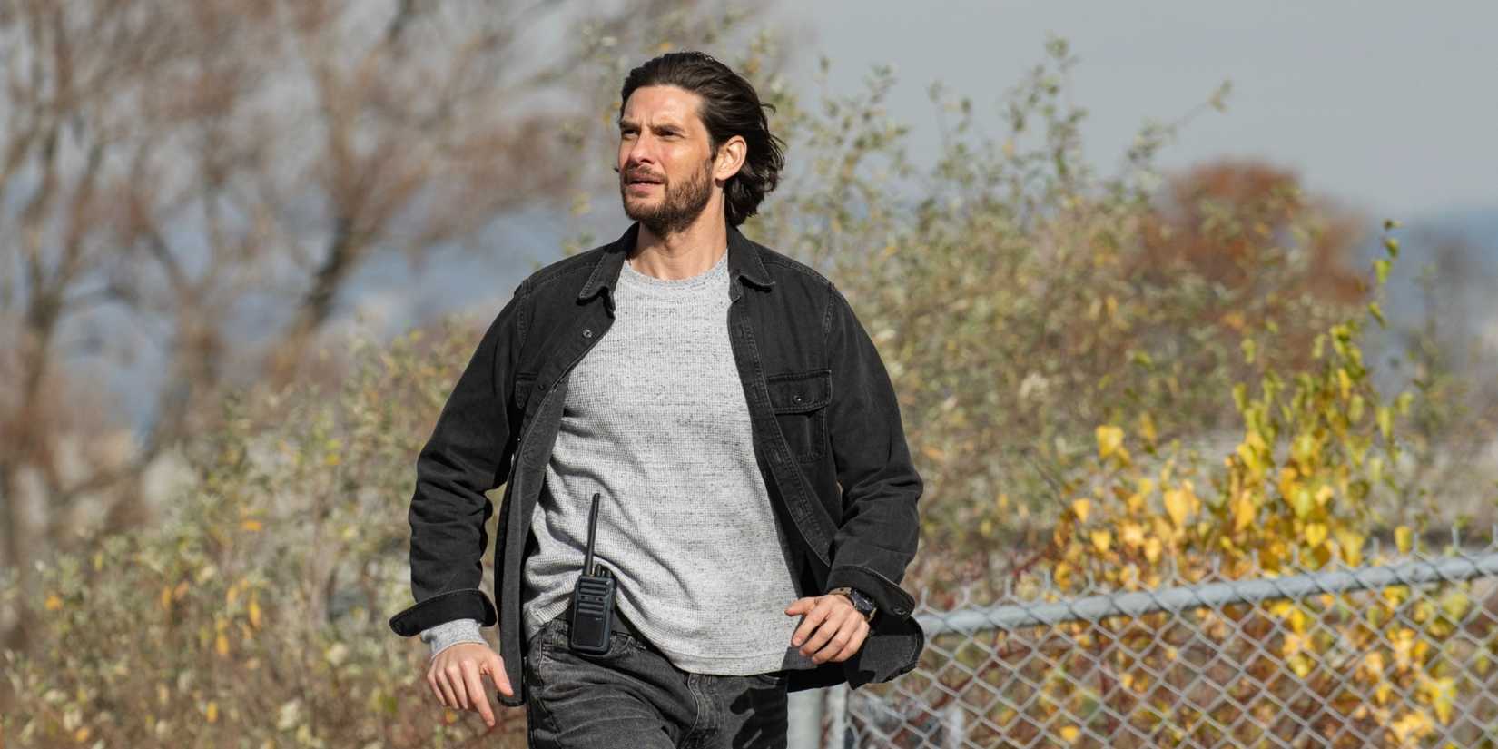 Ben Barnes walks and looks windswept near a fence in The Institute