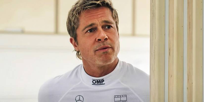 Brad Pitt as Sonny Hayes peering around a doorway in F1 The Movie