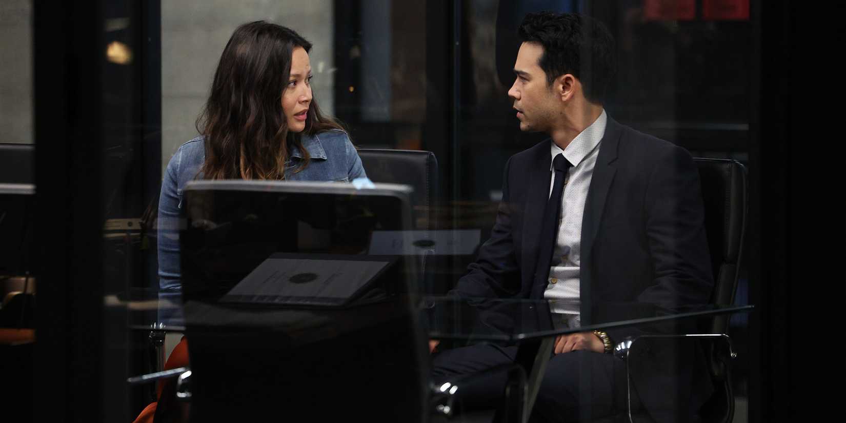 Chris Sanford & Lucy Chen from The Rookie sitting in a conference room in front of a laptop.
