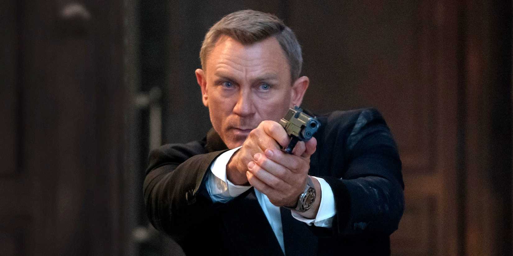 Daniel Craig as James Bond holding a gun in No Time To Die