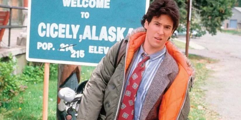 Dr. Joel Fleischman (Rob Morrow) in front of the Cicely Alaska welcome sign in Northern Exposure