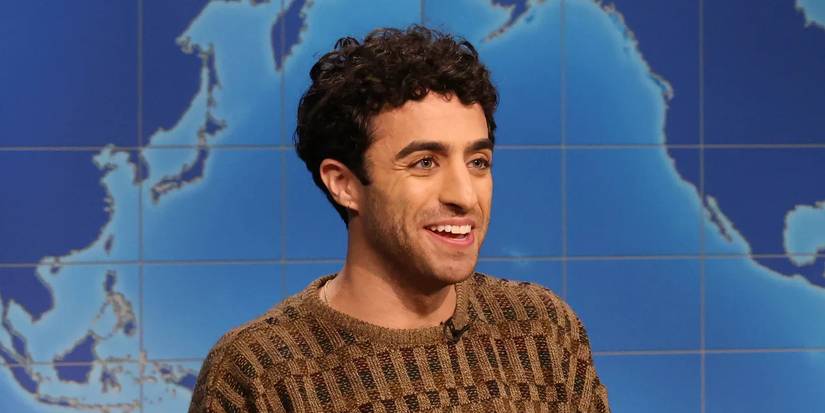 Emil Wakim smiling on the set of Saturday Night Live's Weekend Update set