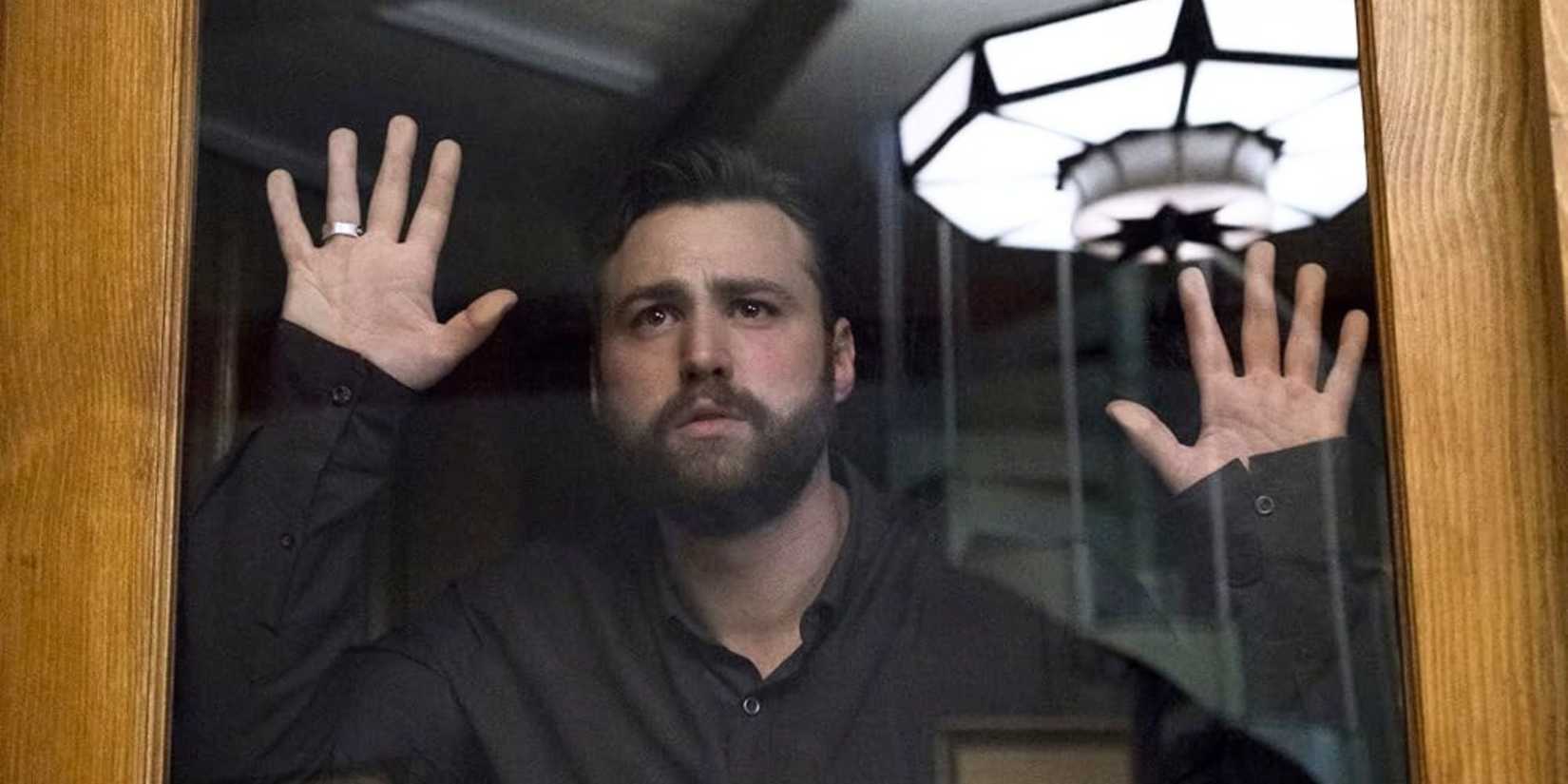 Emory Cohen as Homer, pressed against a glass window staring out at to an unknown distance in The OA