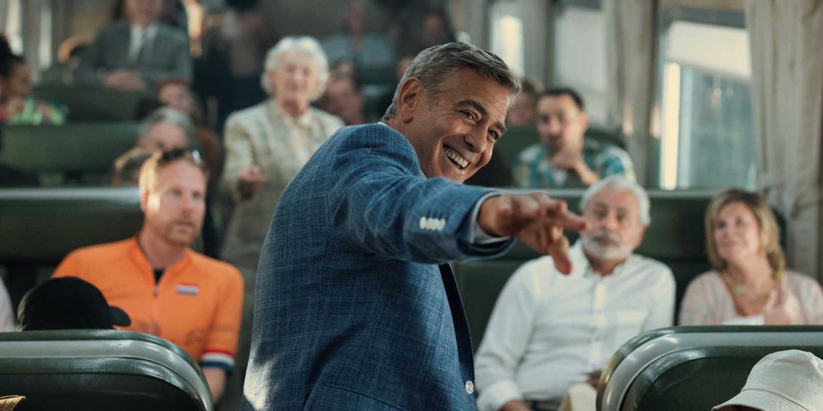 George Clooney sorrindo e apontando em Jay Kelly