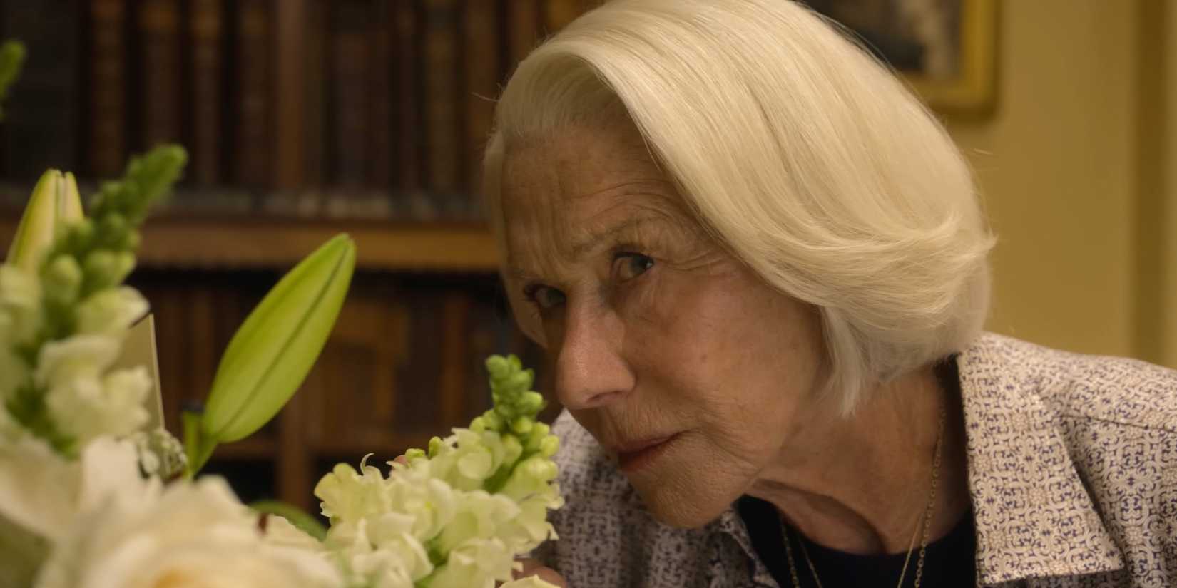 Helen Mirren peering from behind flowers in The Thursday Murder Club 