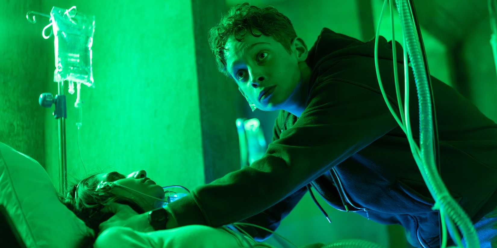 Joe Freeman's Luke looking worried while investigating someone in a bed in The Institute