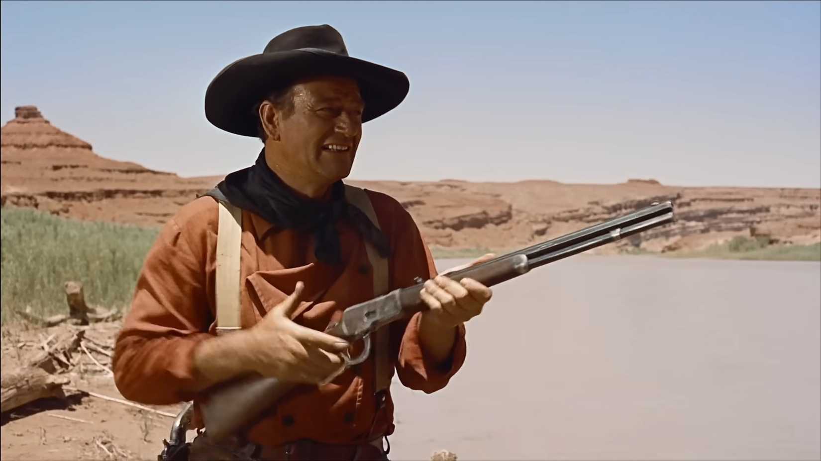 John Wayne como Ethan Edwards em The Searchers, com uma arma.