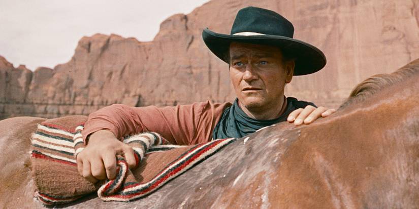 John Wayne as Ethan Edwards looking over a horse in The Searchers