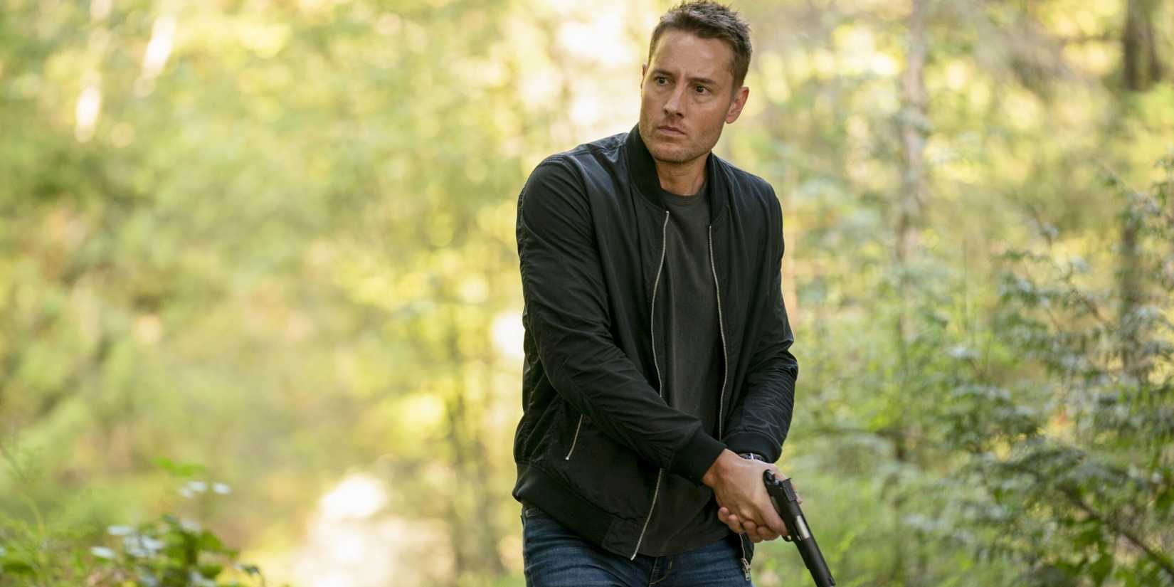Justin Hartley as Colter Shaw with a gun in the woods in the Tracker pilot