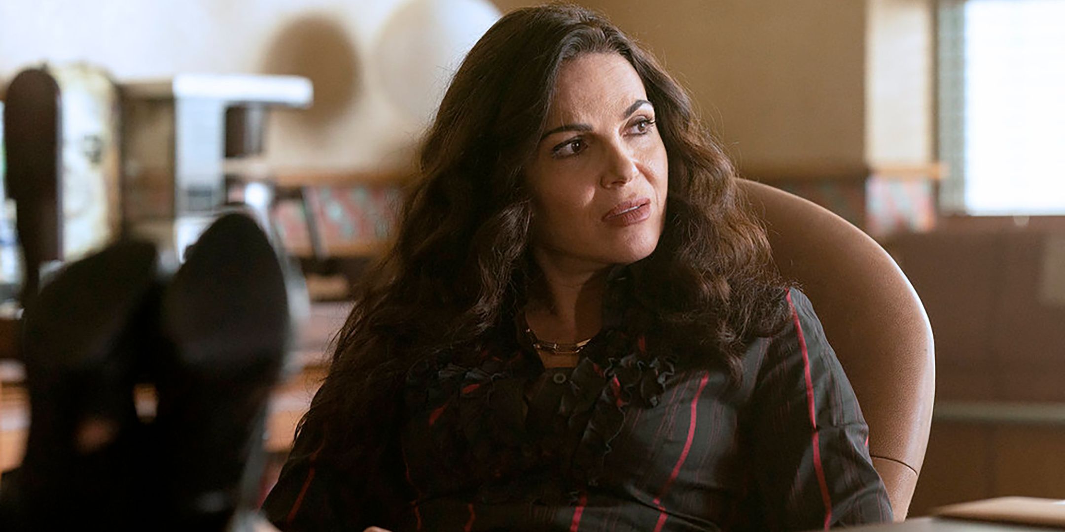 Lana Parrilla as Bruiser looking curious while sitting at her desk in The Rainmaker