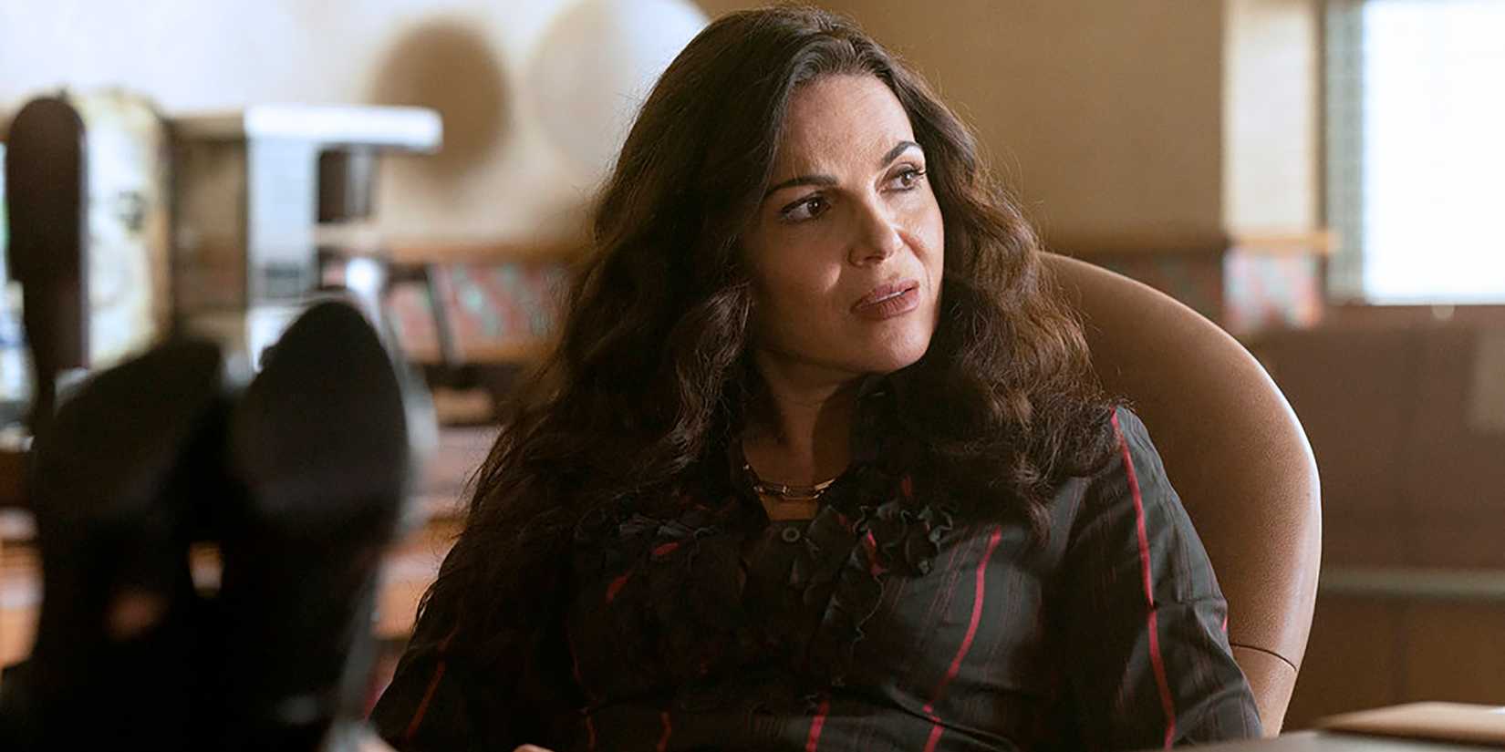 Lana Parrilla as Bruiser looking curious while sitting at her desk in The Rainmaker