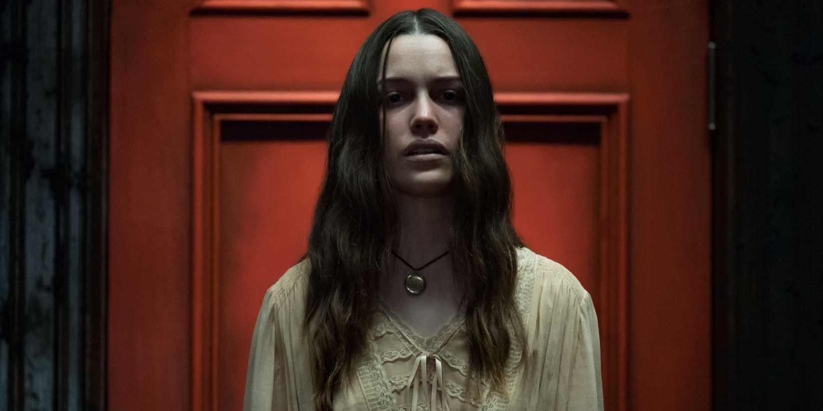 Nell (Victoria Pedretti) standing in front of a red door in The Haunting of Hill House.