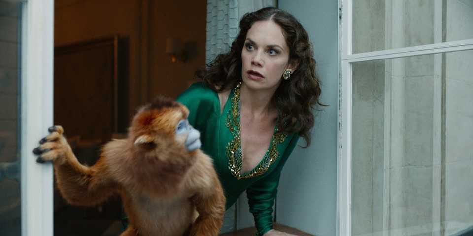 Ruth Wilson as Mrs Coulter looking around a corner with her Daemon in HBO's His Dark Materials