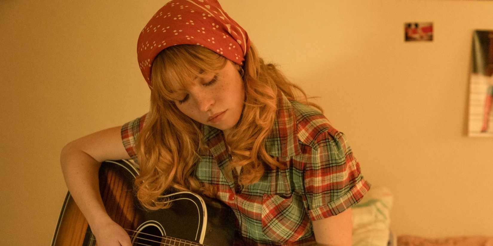 Sydney Sweeney como Penny Jo tocando violão em Americana