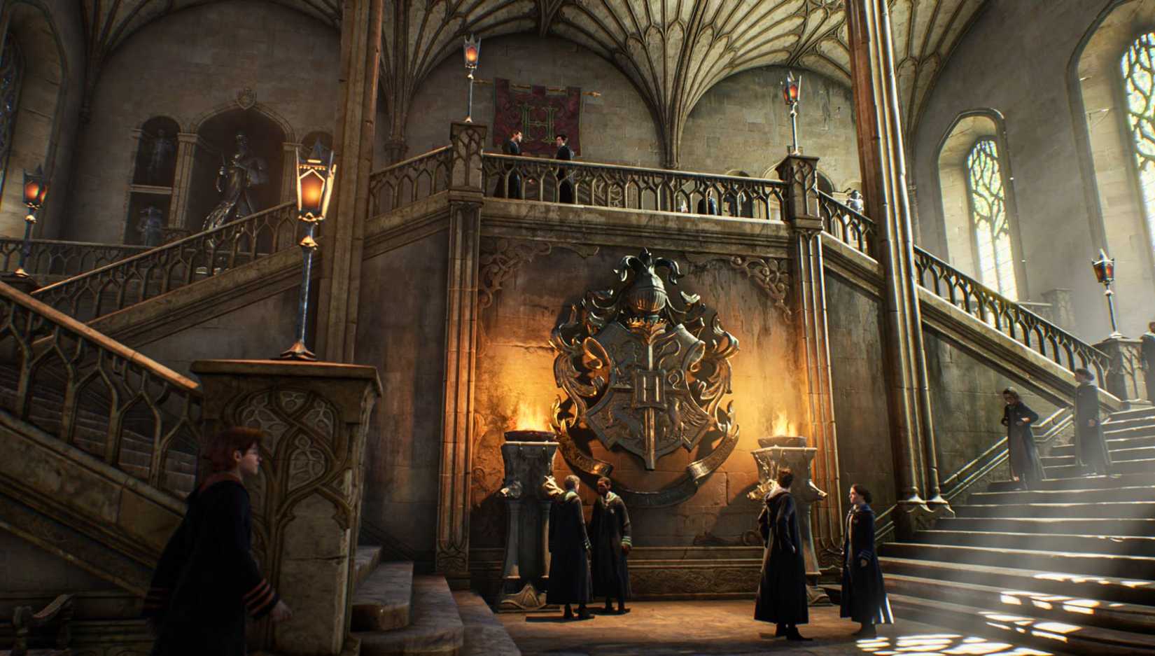 Students standing at the base of the stairs in Hogwarts in front of the school crest in Hogwarts Legacy