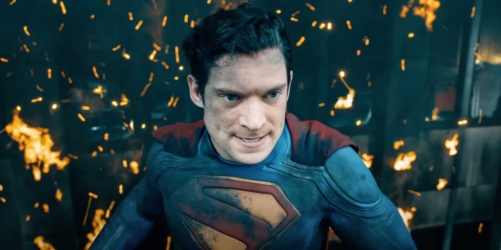 Superman com raiva em frente a um incêndio e um prédio no filme Superman do DCU.