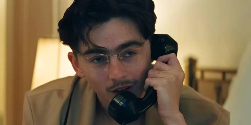 Timothee Chalamet on the phone in a H๏τel room in Marty Supreme