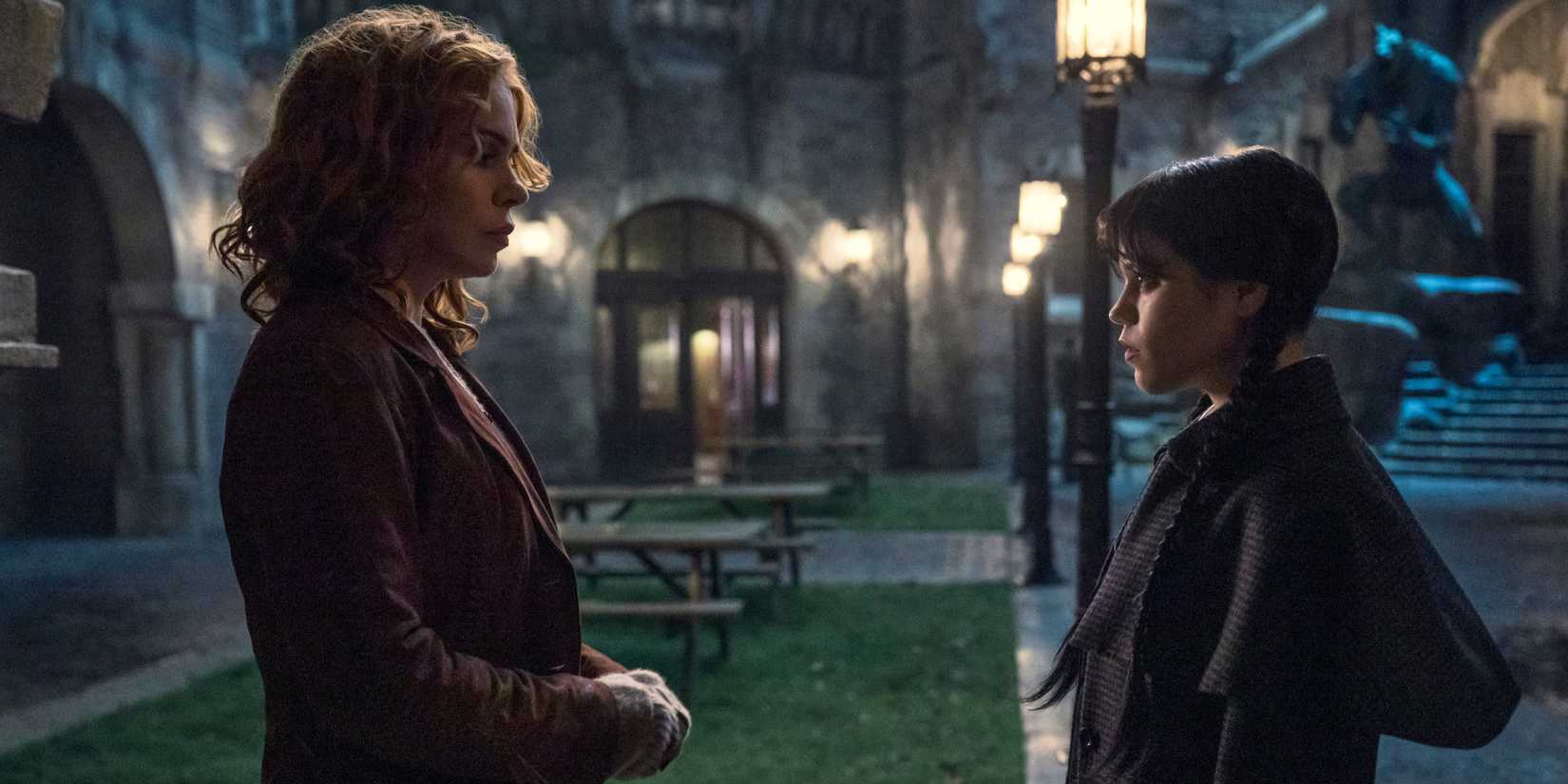 Isadora and Wednesday Addams look at each other while standing in the courtyard in Wednesday season 2.