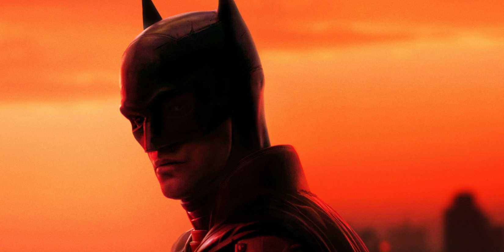 Robert Pattinson as Batman standing on the top of a building in Gotham City