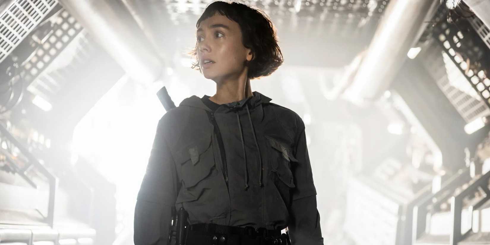 Sydney Chandler as Wendy standing in the brightly lit hallway of a spaceship in Alien: Earth