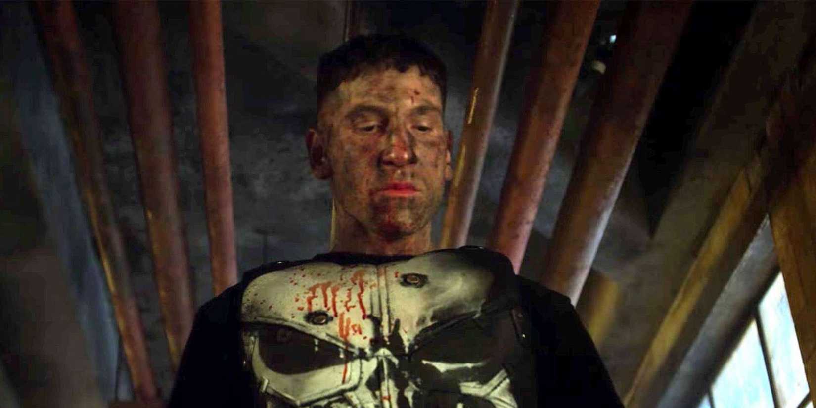O Punisher do MCU, ensanguentado e coberto de fuligem, olhando para baixo.