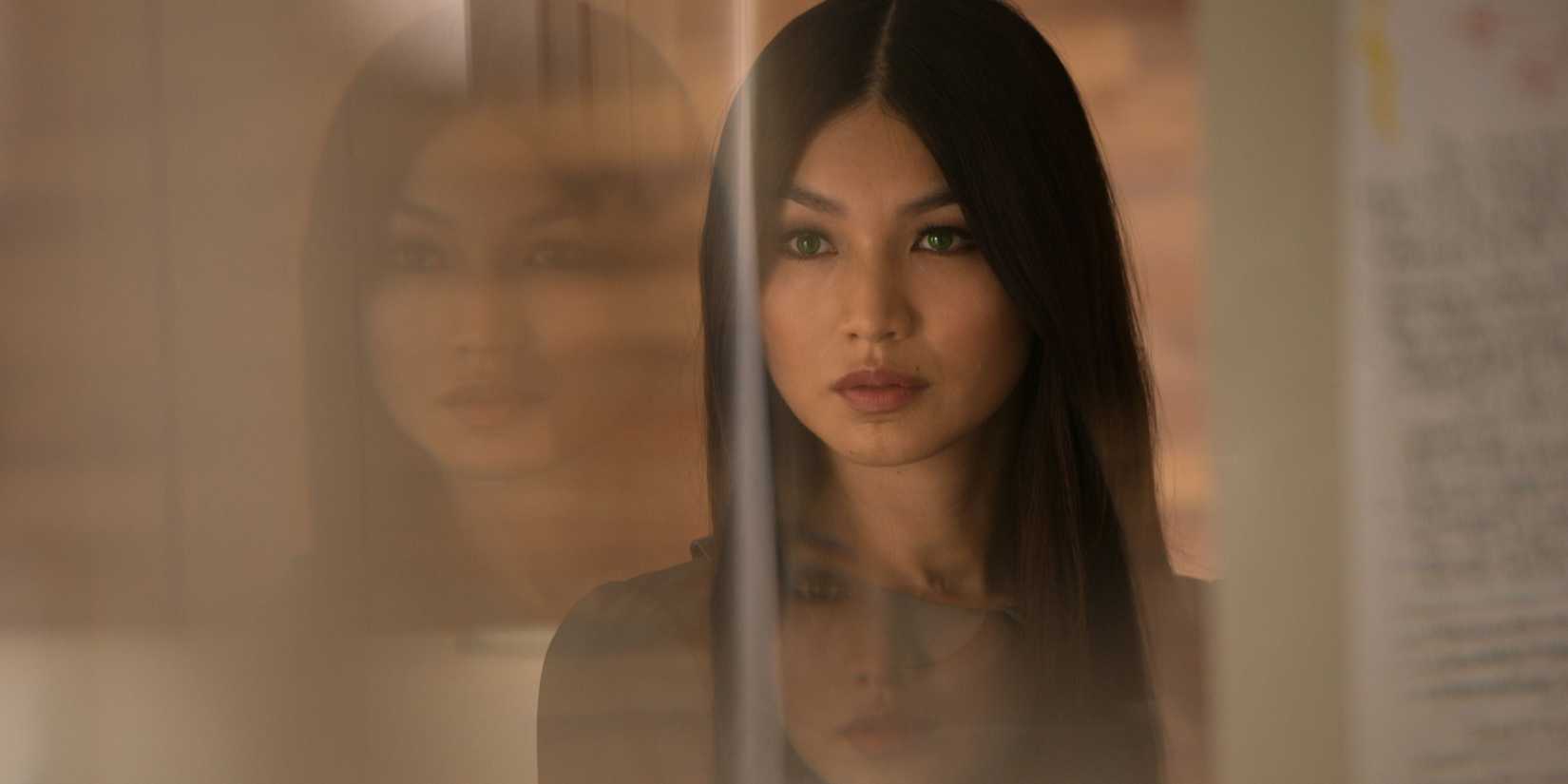 Uma foto promocional de Gemma Chan como Anita Mia olhando para um espelho, reflexões translúcidas olhando para trás, em humanos 