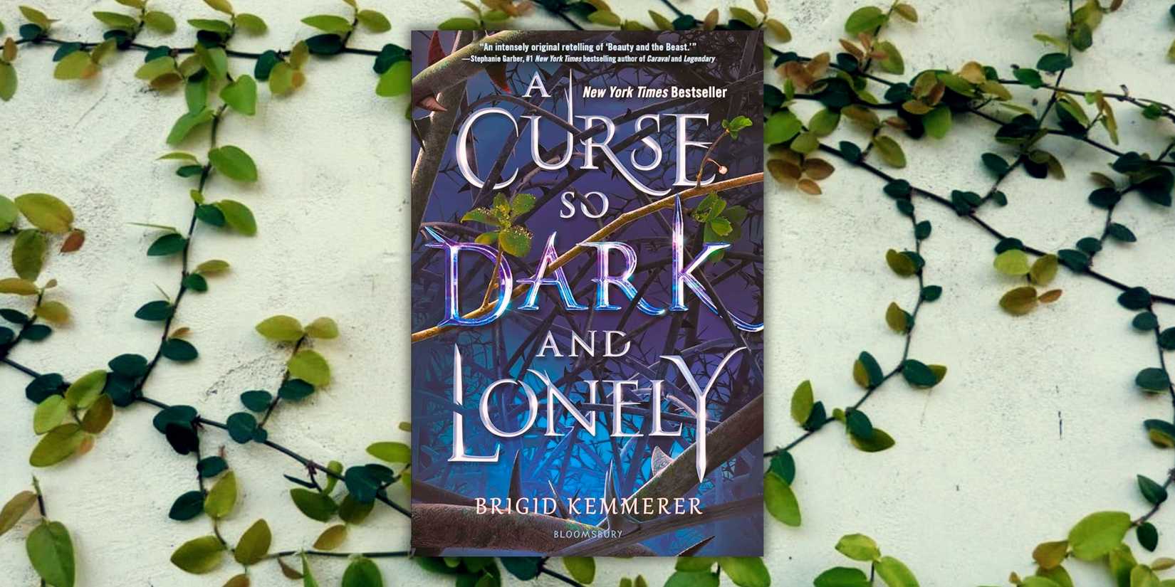 The cover of the book A Curse So Dark And Lonely over a wall of vines