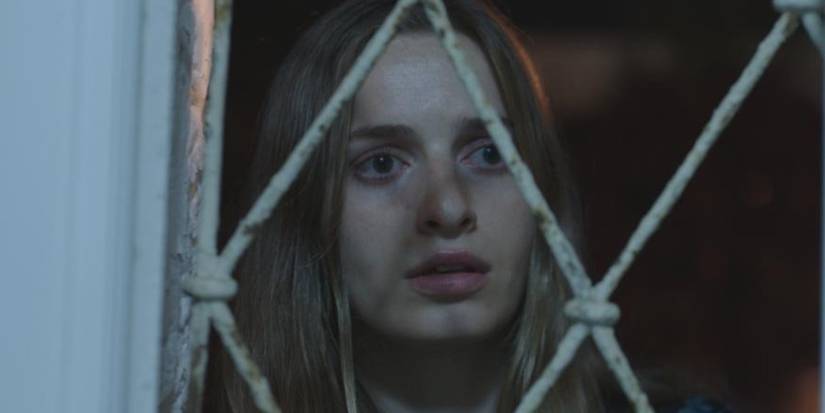 Annie Shapero olhando através de uma janela em céu vermelho