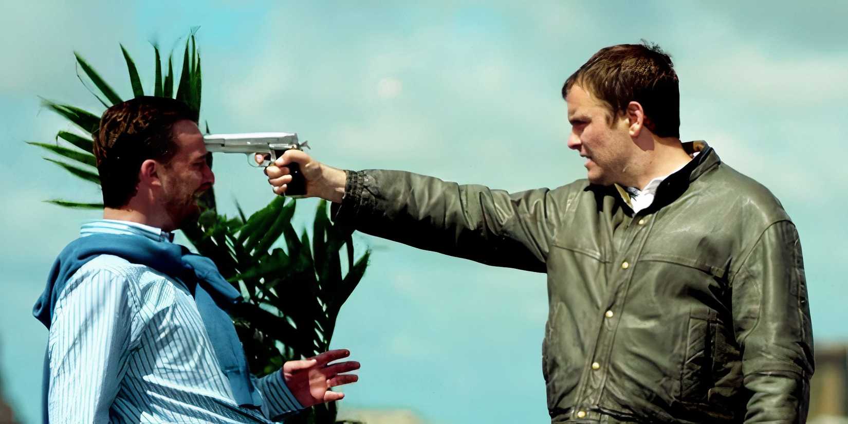 Arby (Nail Maskell) holding a gun to someone's head in the British action show Utopia