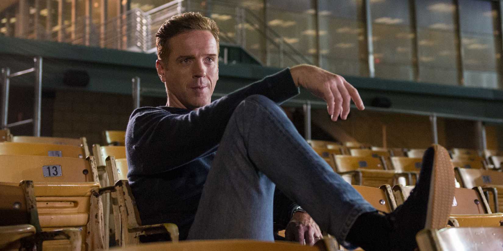 Bobby (Damian Lewis) recostado em um assento de estádio em Billions.