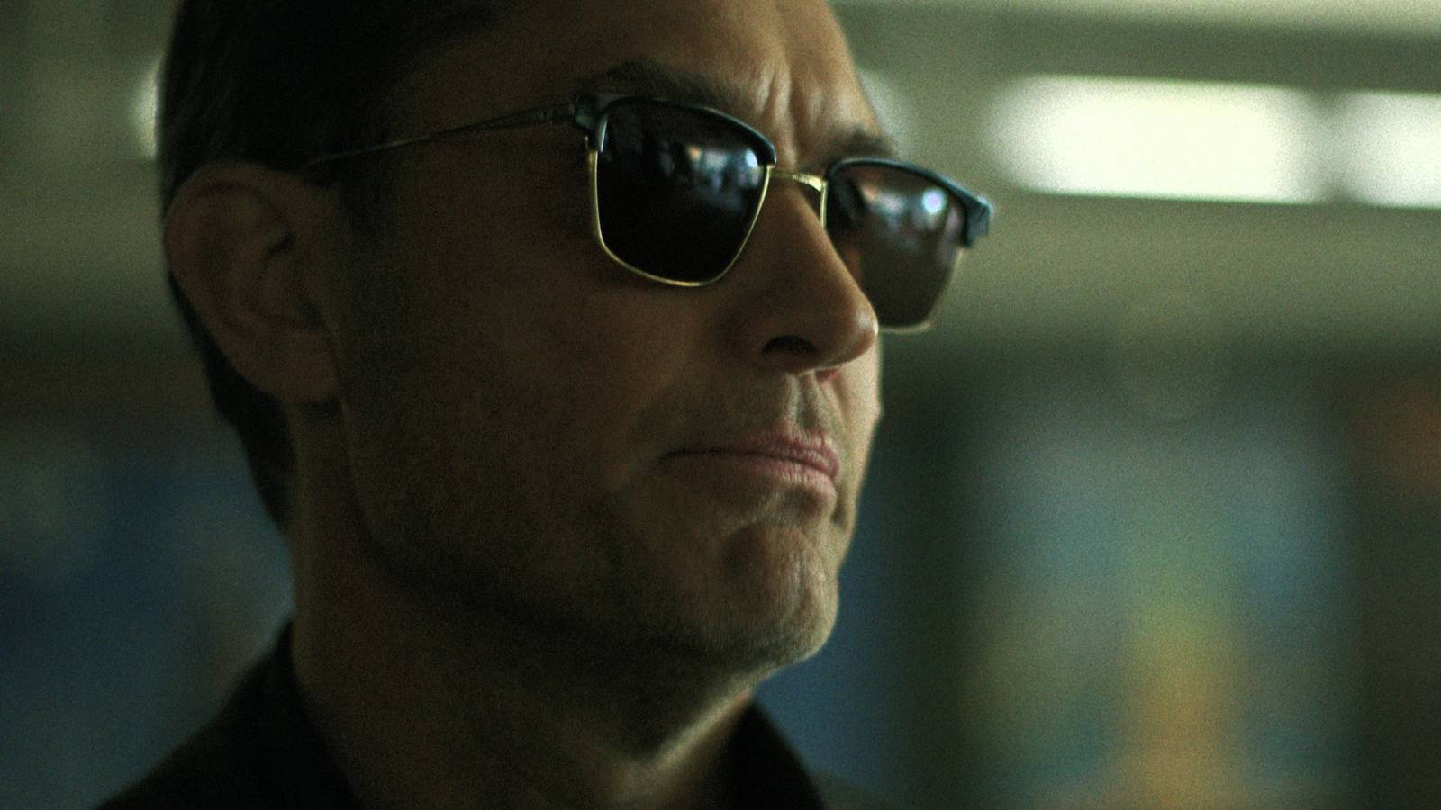 Jude Law's Jake Friedken wears sunglasses and looks to the side in Netflix's Black Rabbit.