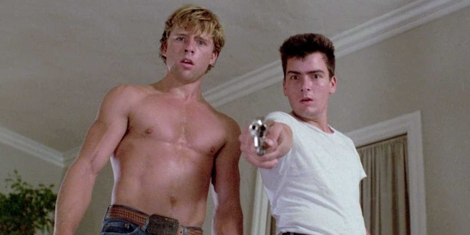 Charlie Sheen as Bo pointing a gun beside Maxwell Caulfield as Roy in The Boys Next Door