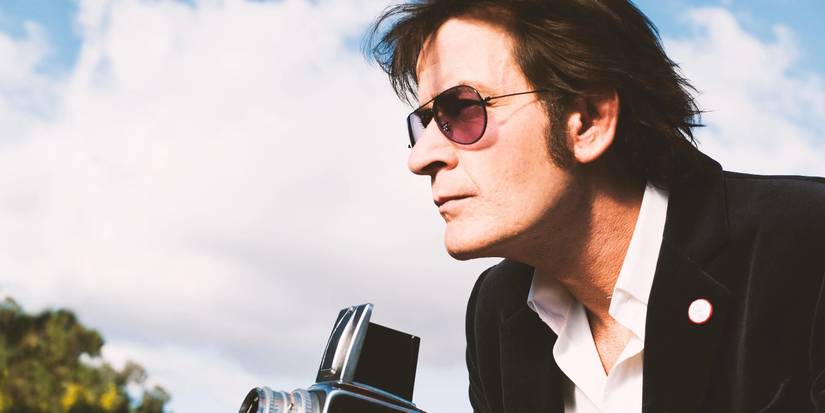 Charlie Sheen as Swan holding a camera in A Glimpse Inside the Mind of Charles Swan III