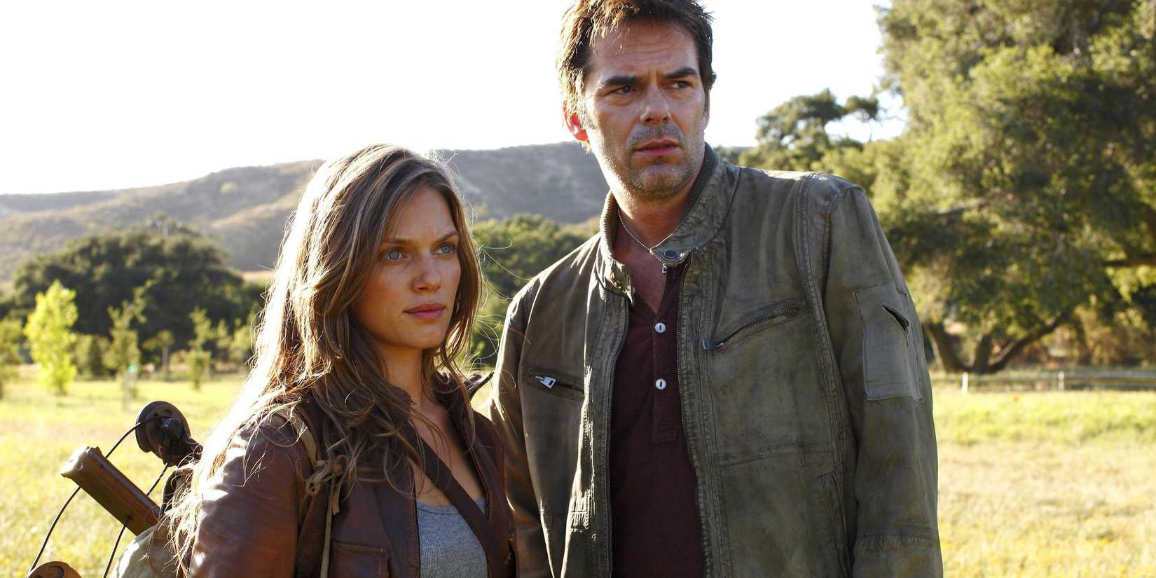 Charlotte and Miles standing in an open field looking at something offscreen in Revolution