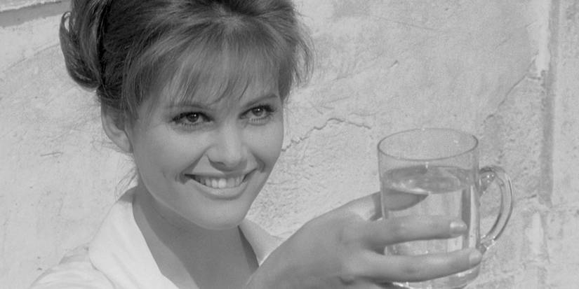 Claudia Cardinale smiles alluringly while holding out a glᴀss of water in a scene from 8 1/2