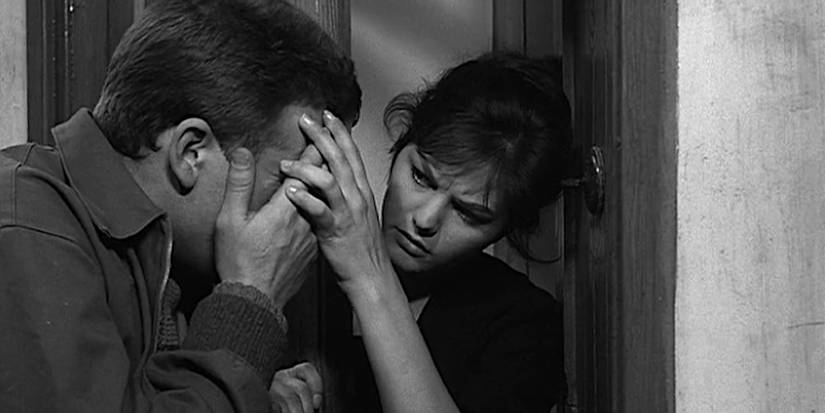 Claudia Cardinale helps an injured man in a doorway in a scene from Big Deal on Madonna Street